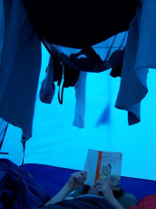 Sarah, reading Watership Down at her end of the tent. Clothes are hung every night to dry them out for the following day.